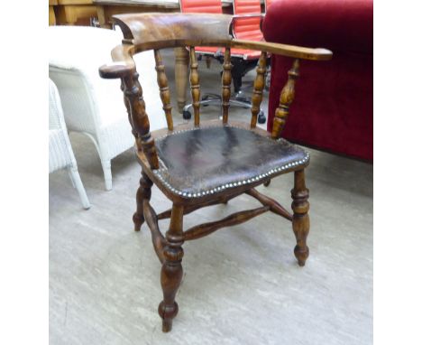 An early 20thC beech, elm and mahogany framed captains desk chair, the stud upholstered hide seat raised on ring turned, tape