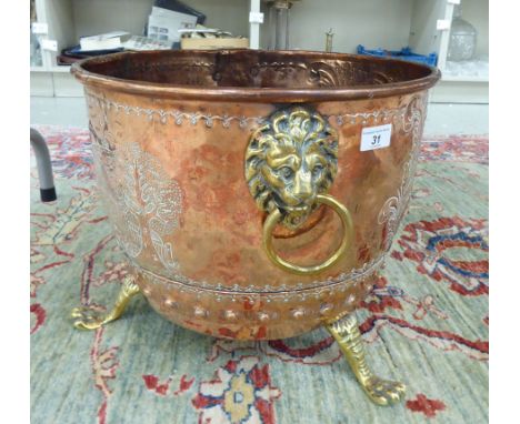 A late Victorian copper and brass log bin, bearing a coat of arms and an opposing pastoral scene with lion mask and ring hand