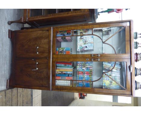 An Art Deco crossbanded walnut finished display cabinet with a pair of glazed doors, enclosing three shelves, over a pair of 