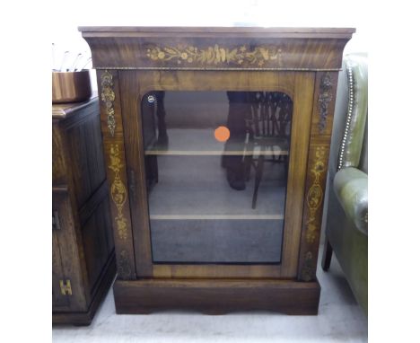 A late Victorian string and marquetry walnut pier cabinet with a glazed door, enclosing two shelves, raised on bracket feet  