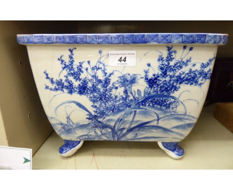 A 20thC Japanese porcelain rectangular planter, on stubby feet, decorated in blue and white with flowers and birds, in a land