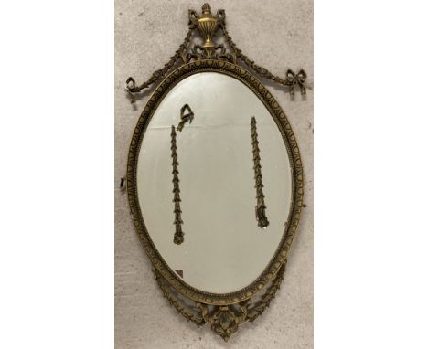 An ornamental vintage gilt framed wall mirror with swag and bow detail.  Oval mirror with bevel edged glass. Frame in need of