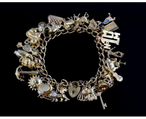 Gold charm bracelet with multiple charms including red enamel ladybird, guitar, roller-skates, all 9ct gold .   Weight 47.5 g