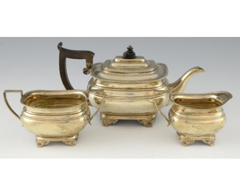 George V silver three piece tea service, comprising teapot, cream jug and sugar bowl with beaded borders, each on four scroll