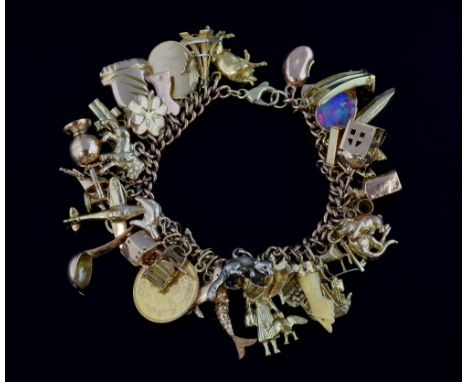 Gold bracelet with charms, including an articulated typewriter, an enamelled plaque Madonna and child, black opal and diamond