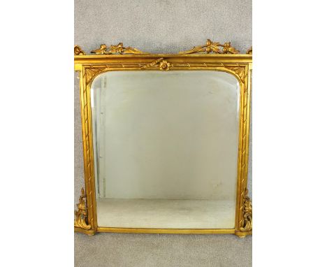 A Victorian giltwood framed overmantel mirror of rectangular form, the bevelled mirrored plate with rounded corners, flanked 
