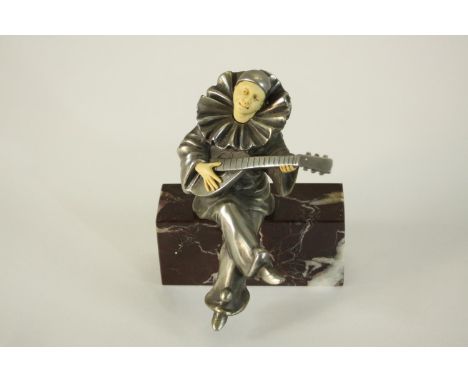 After Chiparus, a spelter and resin figure of a clown playing the lute on a red marble base. H.14 W.10 D.10cm. 