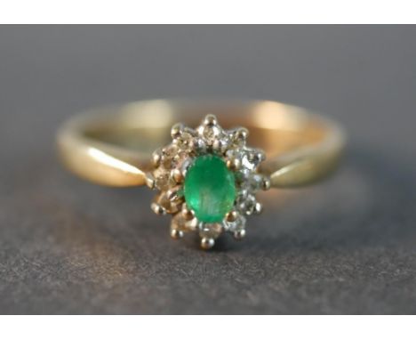 A 9 carat gold vintage emerald and diamond cluster ring, set to the centre with an oval mixed cut emerald with an approximate