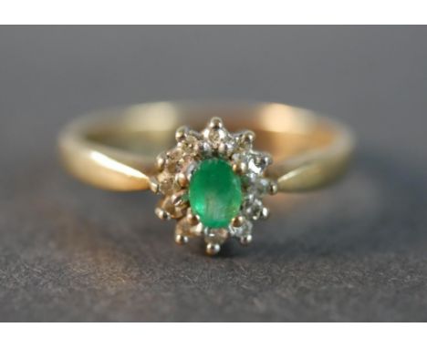 A 9 carat gold vintage emerald and diamond cluster ring, set to the centre with an oval mixed cut emerald with an approximate