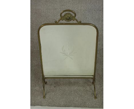 A circa 1900 brass mirrored fire screen, with engraved foliate design to the centre of the mirror plate. H.69 W.39 D.19cm. 