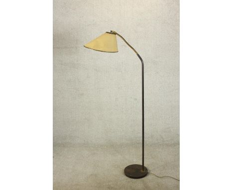 A 1950's standard lamp, with an adjustable brass arm on a black painted stem with a circular black painted base, and a shaped