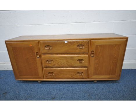 A MID CENTURY ELM ERCOL WINDSOR ROLLING SIDEBOARD, fitted with two cupboard doors, flanking three drawers, top drawer with cu