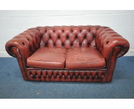 AN OXBLOOD BUTTONED LEATHER TWO SEATER CHESTERFIELD SOFA, length 152cm x depth 89cm x height 66cm (condition report: rips and