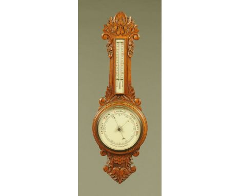 An early 20th century carved oak Aneroid barometer, with ceramic dial and scale.  81 cm.