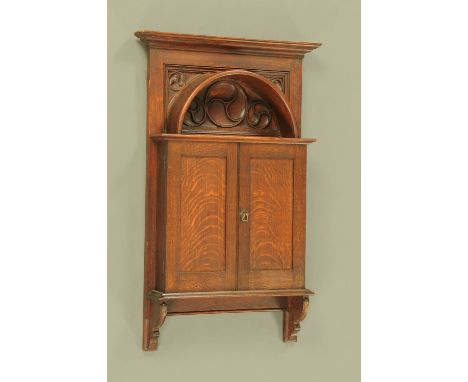 A late 19th/early 20th century Arts &amp; Crafts hanging cupboard, with arched top and shelf above a pair of doors opening to