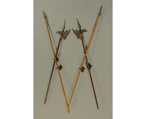Four facsimile pike staffs, two with spear ends and two with axe ends.  Each length 263 cm and complete with wall brackets.  