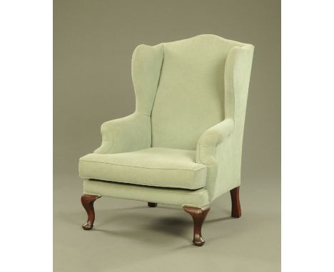 A Queen Anne style mahogany wing easy chair, with loose cushion upholstered in green velvet type material and raised on front