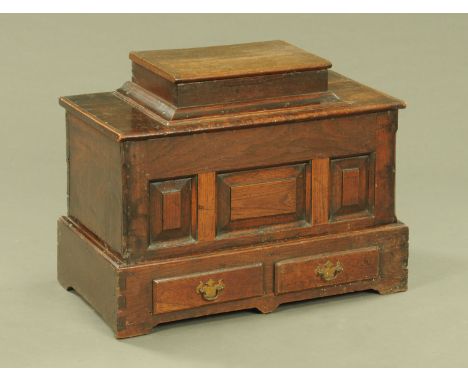 An 18th century small oak Bach coffer, with hinged box top, three panelled front, fitted with two drawers beneath and raised 