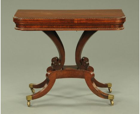 A Regency mahogany turnover top card table, with carved beaded edge with baize interior surface raised on four splayed suppor