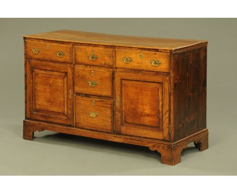 An antique elm dresser, with moulded edge and fitted with a series of drawers and cupboards raised on bracket feet.  Height 7