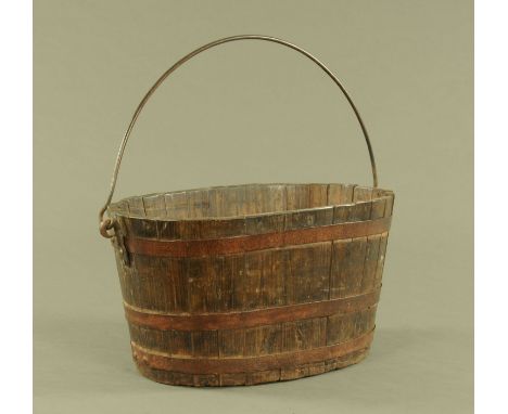 A 19th century oval oak metal bound barrel form planter, with iron loop handle.  width excluding handles 59 cm, depth 34.5 cm