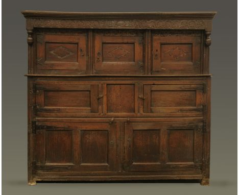 A 17th century inlaid oak court cupboard dated 1621, with moulded cornice above a carved frieze and three panelled doors abov