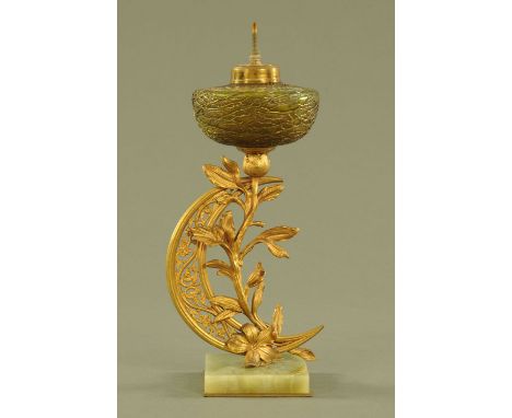 An Art Nouveau gilt brass lamp base, with iridescent glass font and raised on an onyx base, the crescent signed but difficult