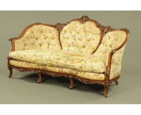 A Victorian style wooden framed settee, foliate and scroll carved, with deep buttoned back and stuffover seat with loose cush