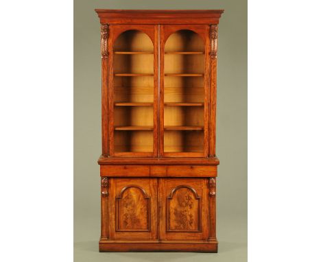 A Victorian mahogany bookcase on cupboard in two sections, the top half with a moulded cornice above a pair of arched glazed 