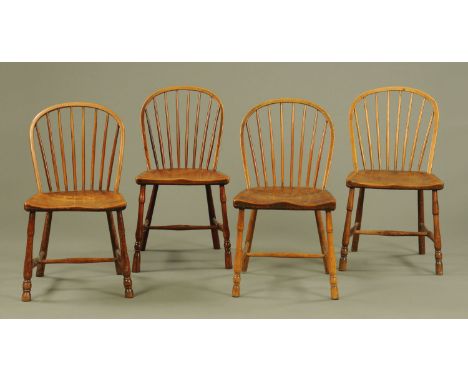 A set of four early 19th century elm dining chairs, with arched stick backs, solid seats and raised on turned legs united by 