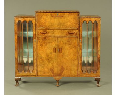 An Art Deco walnut veneered cocktail cabinet, with carved moulded edge and fitted with a series of drawers and cupboards.  He