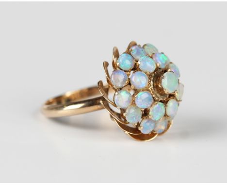 A gold and opal cluster ring, mounted with three tiers of circular opals in a flowerhead shaped design, detailed '18K', weigh