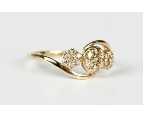 A 9ct gold and champagne diamond ring in a triple cluster twistover design, mounted with circular cut diamonds, weight 2.2g, 