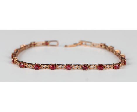 A gold and ruby bracelet, claw set with circular cut rubies alternating with scroll pierced links, on a foldover clasp, detai