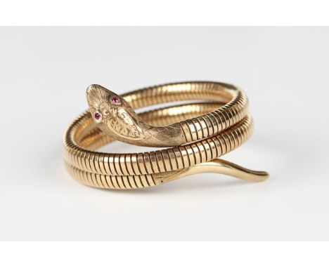 A 9ct gold and synthetic ruby bracelet, designed as a coiled snake, the head with engraved decoration and synthetic ruby set 