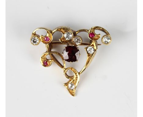 A gold, ruby, red spinel and diamond brooch in a scroll pierced openwork design, claw set with the cushion cut red spinel to 