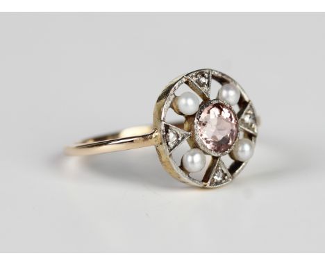 A gold ring, collet set with the circular cut pink tourmaline within a pierced openwork surround, set with four seed pearls a