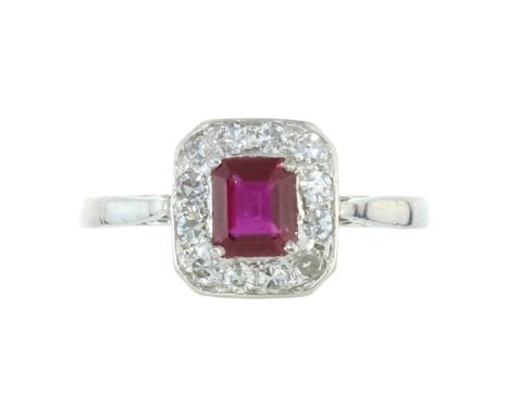 A RUBY AND DIAMOND CLUSTER RING in platinum or white gold, set with a central step cut ruby of 0.63 carats encircled by round