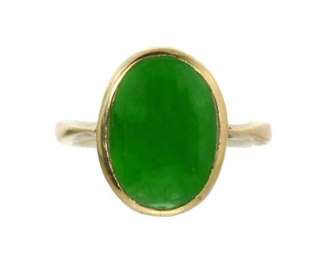 A JADEITE JADE DRESS RING in high carat yellow gold, set with an oval cabochon piece of jade within a plain gold mount, appar