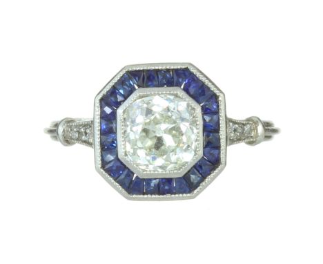 A DIAMOND AND SAPPHIRE DRESS RING in platinum or white gold set with a central old mine cut diamond of 1.35 carats encircled 