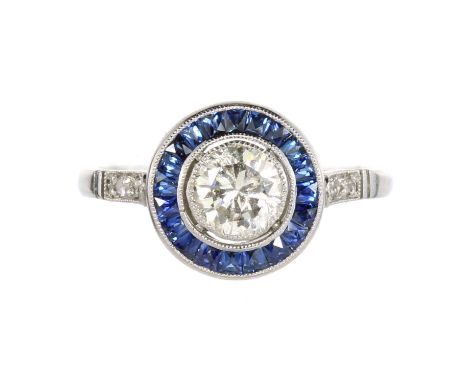 A DIAMOND AND SAPPHIRE DRESS RING in platinum or white gold, set with a central round cut diamond of 0.61 carats, encircled b