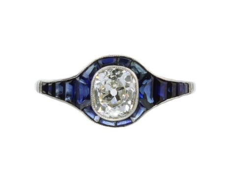 A DIAMOND AND SAPPHIRE DRESS RING in white gold or platinum, set with a central old mine cut diamond of 1.0 carats within a c