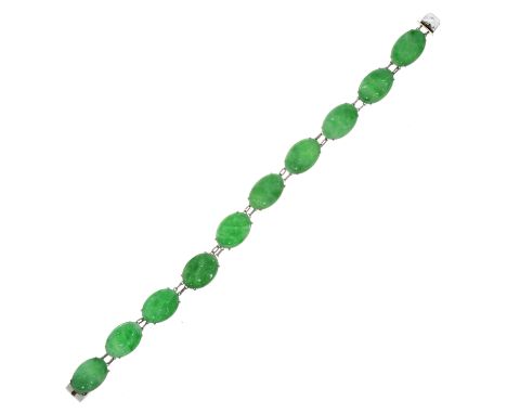 A CARVED JADEITE JADE BRACELET in white gold or platinum, comprising a single row of ten oval carved cabochon pieces of jade 