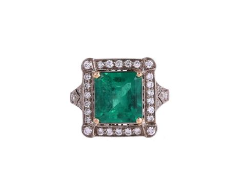 A FRENCH EMERALD AND DIAMOND CLUSTER RINGThe step cut emerald with canted corners estimated to weigh 2.73 carats, within a su