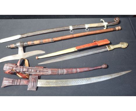 FOUR EDGED WEAPONS including three tribal swords with leather scabbards and a tribal axe
