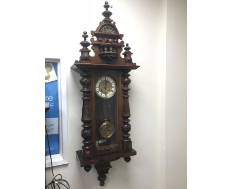An Antique mahogany wall clock, Styled with an enamel and art nouveau brass face. Running condition. Measures 120cm in height