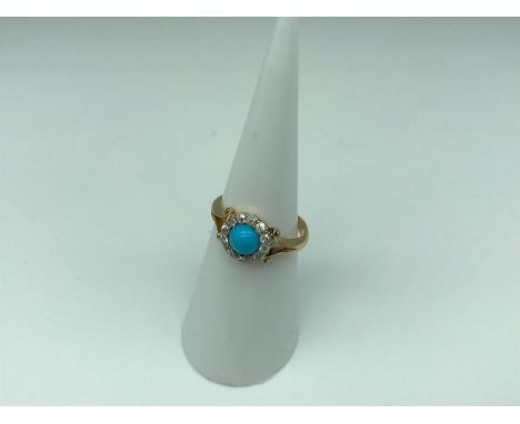 A 15ct gold ladies ring styled with a large turquoise stone, circled by clear stones (possibly diamonds) 