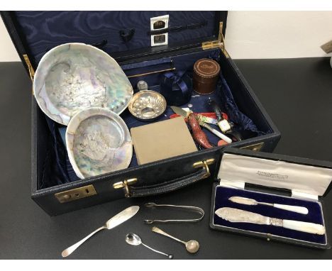 A Vintage case filled with various collectables. Includes silver flatwares, 2 Mother of pearl shells, White metal porringer a