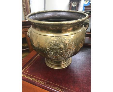 A large brass antique planter. Has a Family crest to the front and lion heads to the sides. Measures 38cm in height. 
