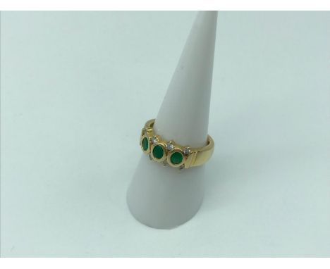 Ladies 18ct gold dress ring, set with three large emerald stones and offset with eight diamonds, size O, 5 grams in weight